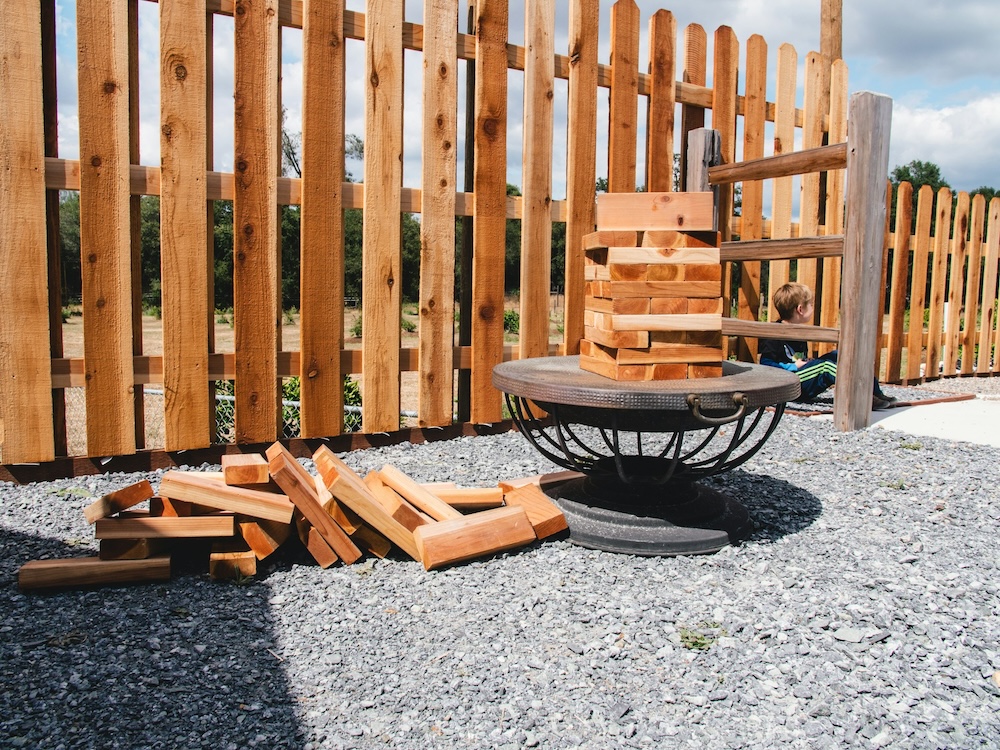 Wooden Fence With Wood In Front of It Stacked up